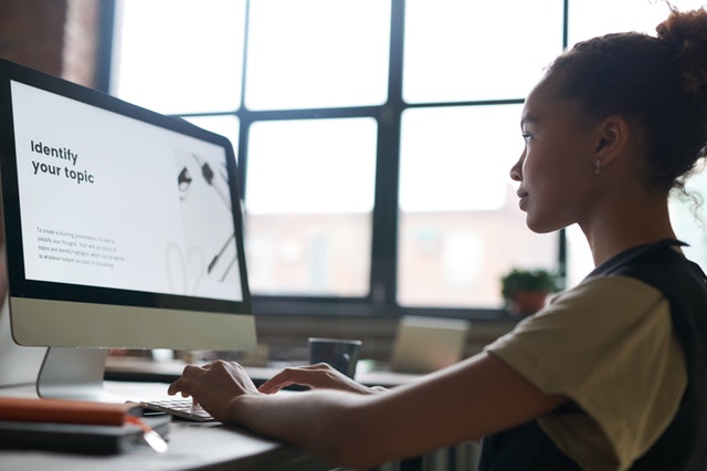 a lady typing something on a large desktop